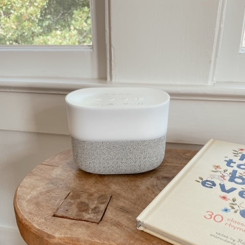 Sound machine sitting on wood table next to childrens book