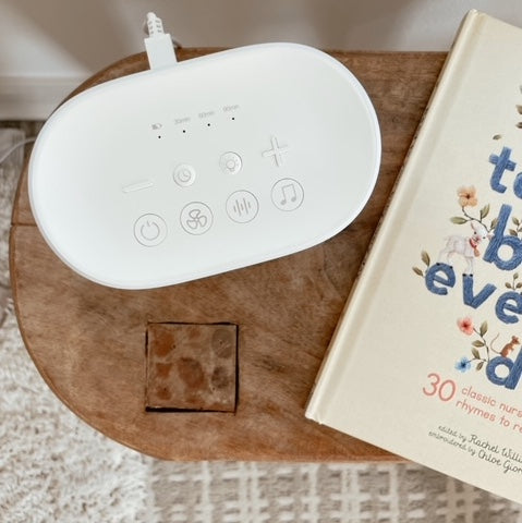 Over head view of sound machine sitting on wood table next to childrens book