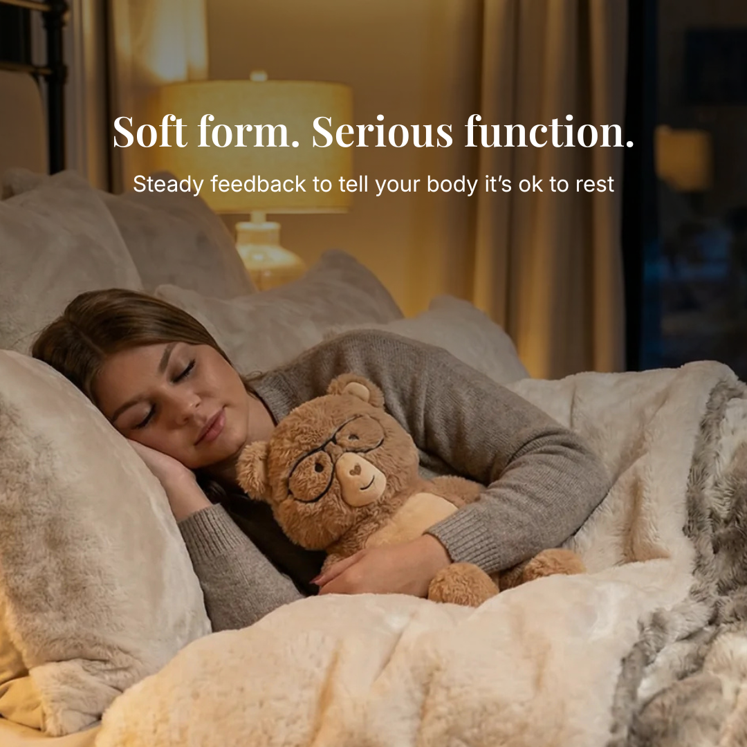 Person lying in bed with a teddy bear, surrounded by soft bedding and pillows.