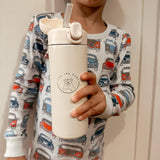 Young boy holding cream water bottle with cap off and silicone straw showing