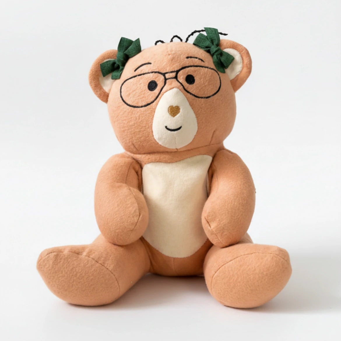 Plush Penny bear with glasses and a green leaf on a white background