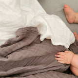 Snow and silver muslin quilt with baby hand and foot shown