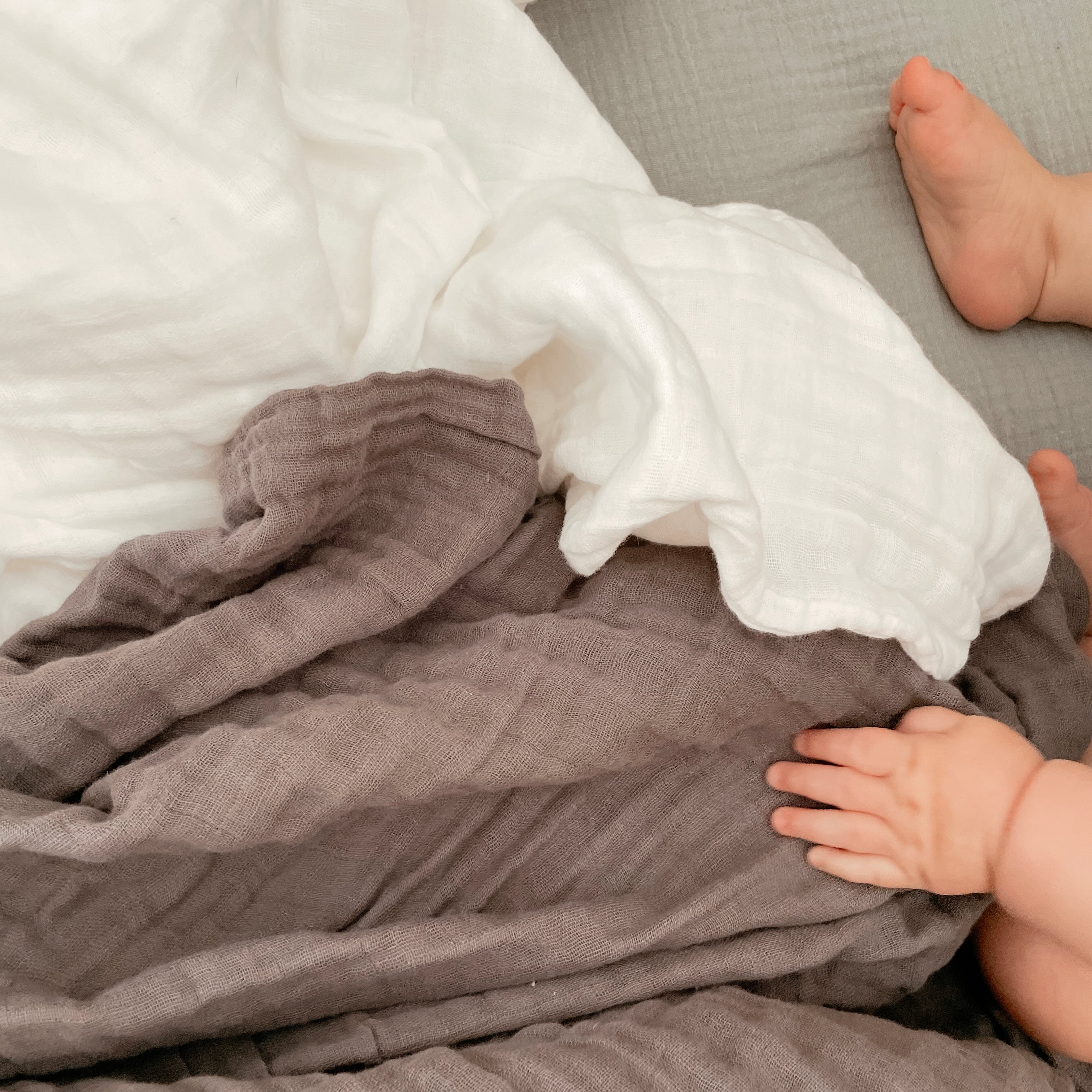 Snow and silver muslin quilt with baby hand and foot shown