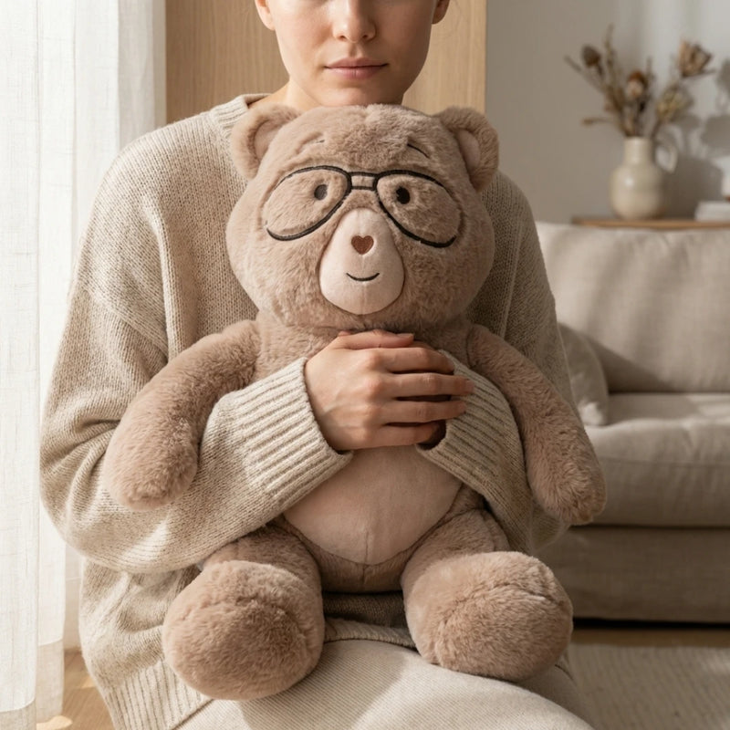 Person holding Percy bear with glasses in a cozy living room.