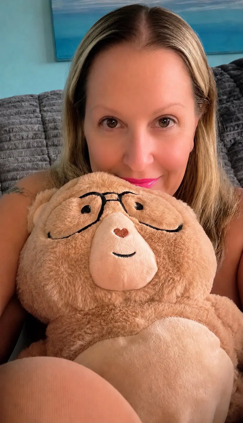 Woman holding a Percy bear with glasses and a heart nose in a casual setting.