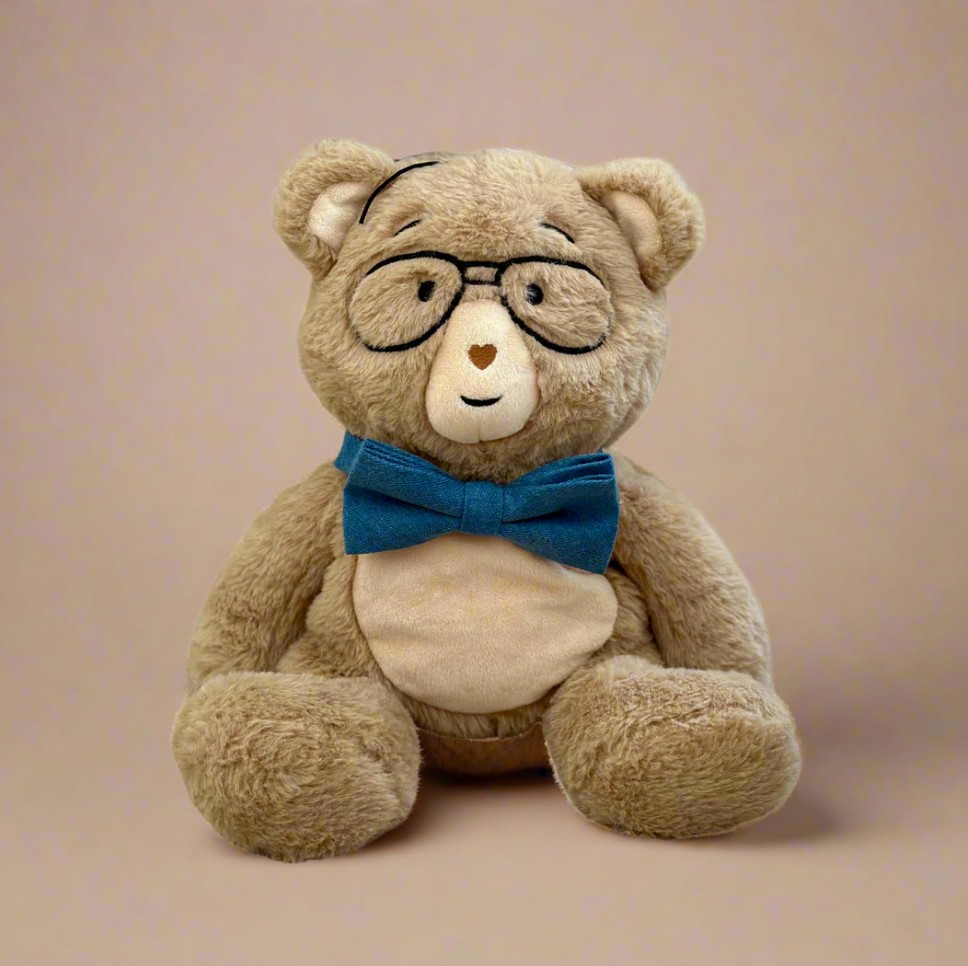 Teddy bear wearing glasses and a blue bow tie on a beige background