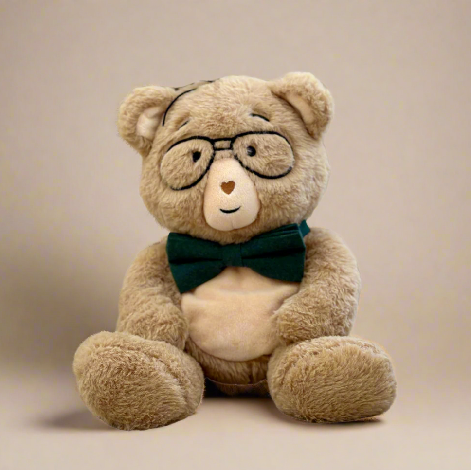 Teddy bear wearing glasses and a green bow tie on a beige background