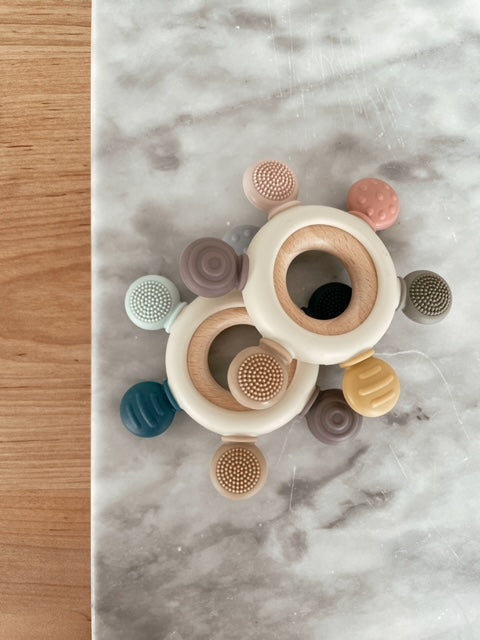 Over head view of wood and silicone teethers on marble and wood backgrounds