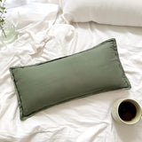 Green pillow on a white bed with a cup of coffee and a plant.