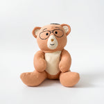 Plush Penny teddy bear with glasses on a white background