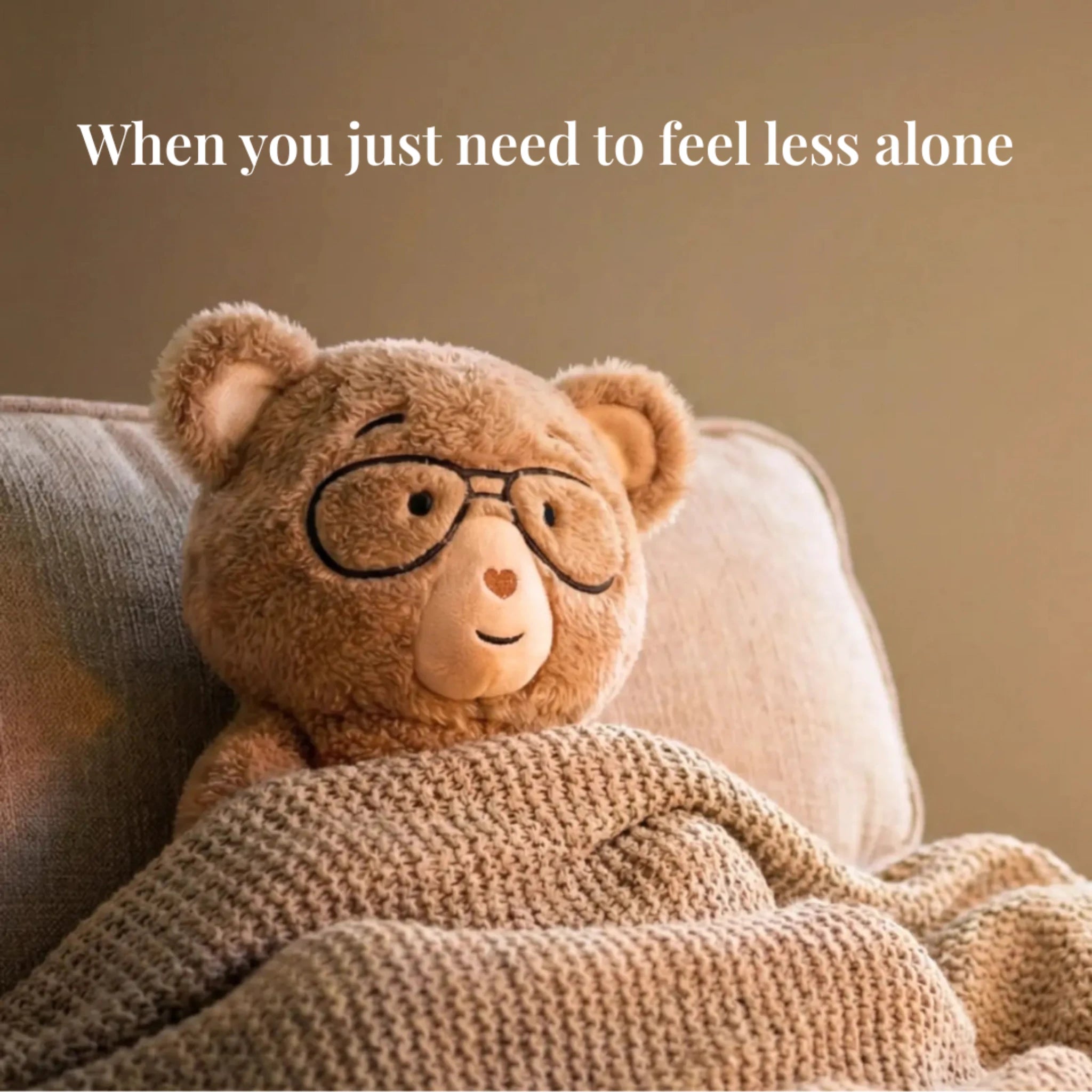 Percy bear wearing glasses and wrapped in a blanket on a couch with text 'When you just need to feel less alone'.